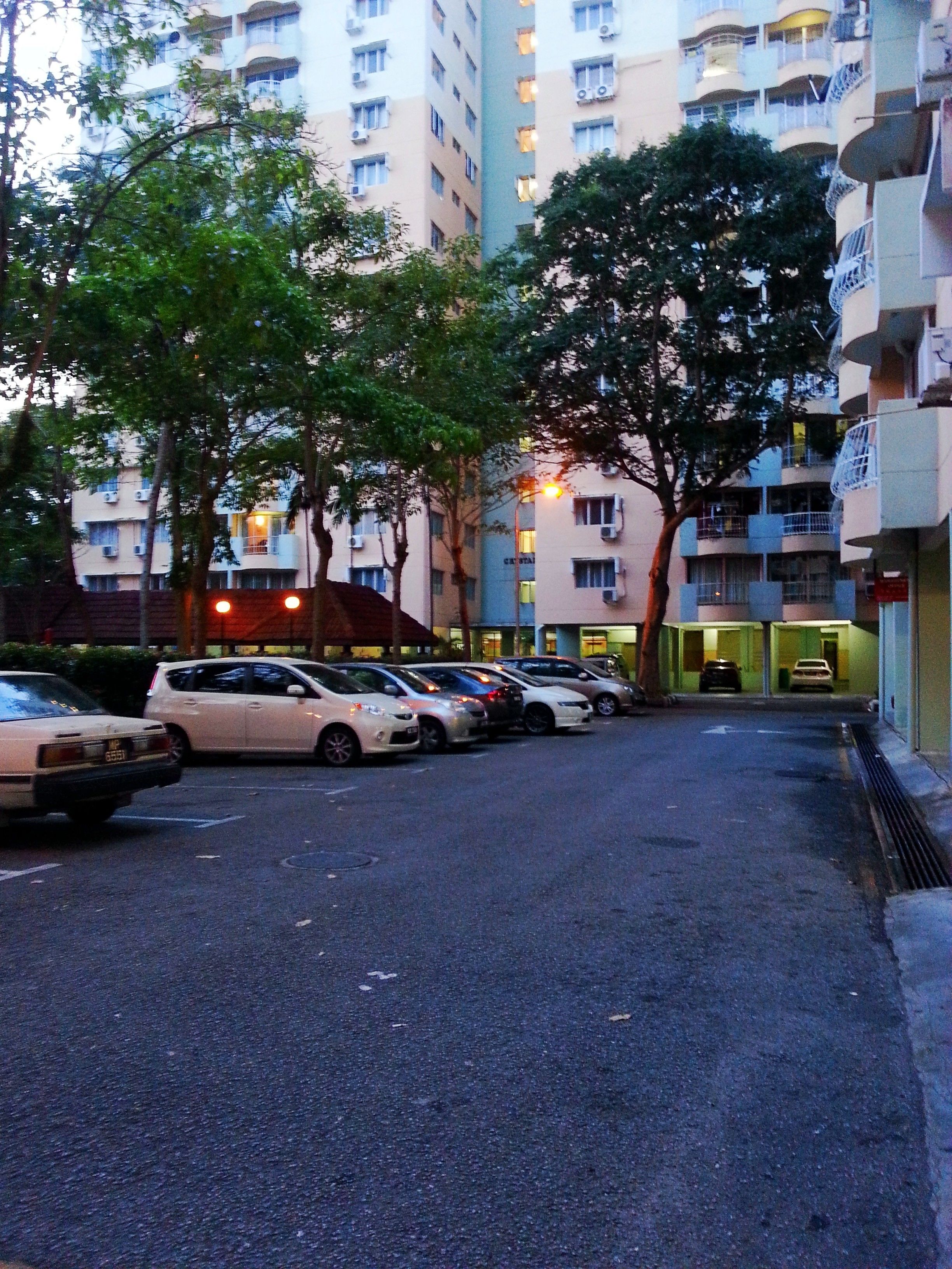 A parking lot with several cars parked in front of a multi-story building with balconies.
