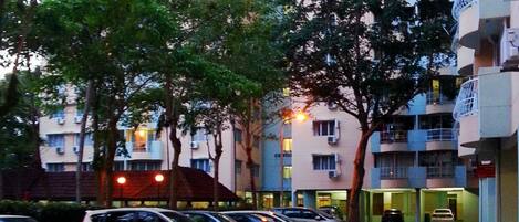 A parking lot with several cars parked in front of a multi-story building with balconies.