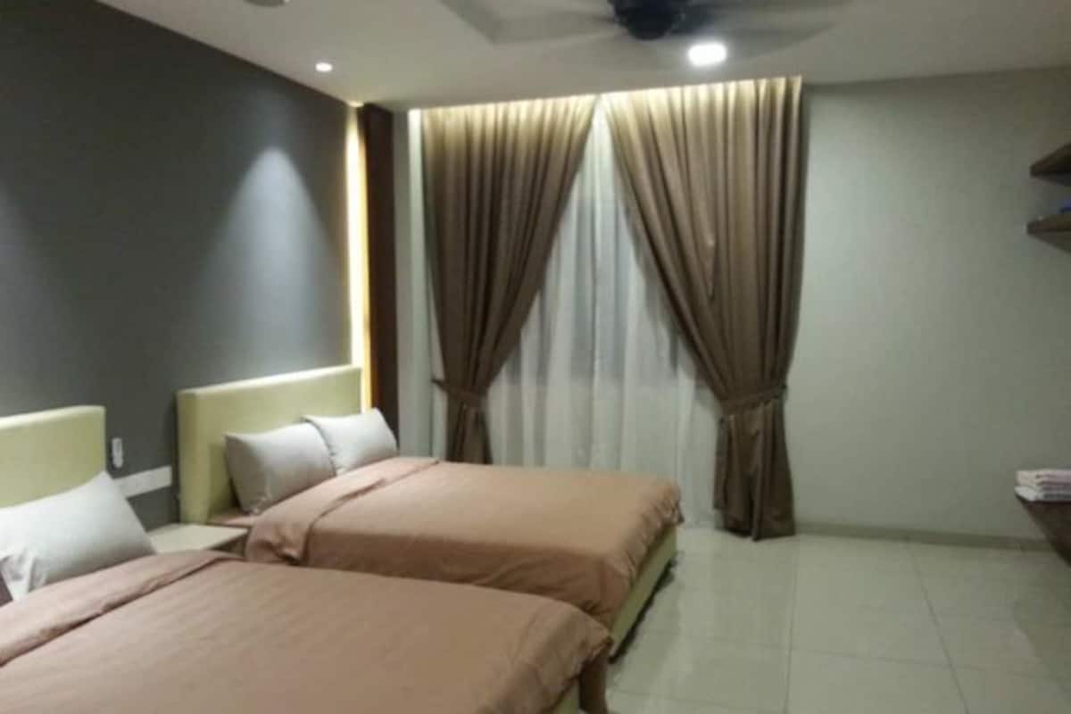 A hotel room with two beds, a nightstand, a lamp, and a window with curtains.