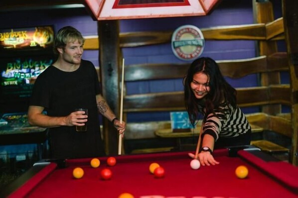 A pool table with balls, a dartboard, and a neon sign in a bar setting. - Beaches Backpackers Airlie Beach - Hostel (Airlie Beach)