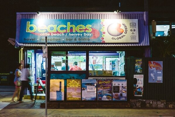 Een strandbar en bistro genaamd 'beaches' met een receptie en diverse posters die lokale bezienswaardigheden promoten.