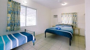 Habitación con dos camas individuales, una ventana con cortinas, ventilador de techo y aire acondicionado de pared.
