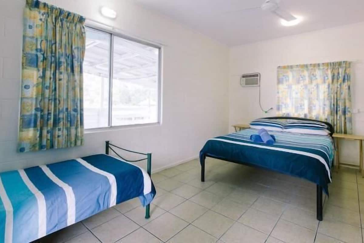 Habitación con dos camas individuales, una ventana con cortinas, ventilador de techo y aire acondicionado de pared.