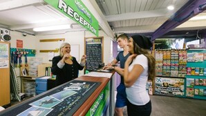 Zona de recepción con mostrador, un letrero verde en la parte superior y un tablón de anuncios.