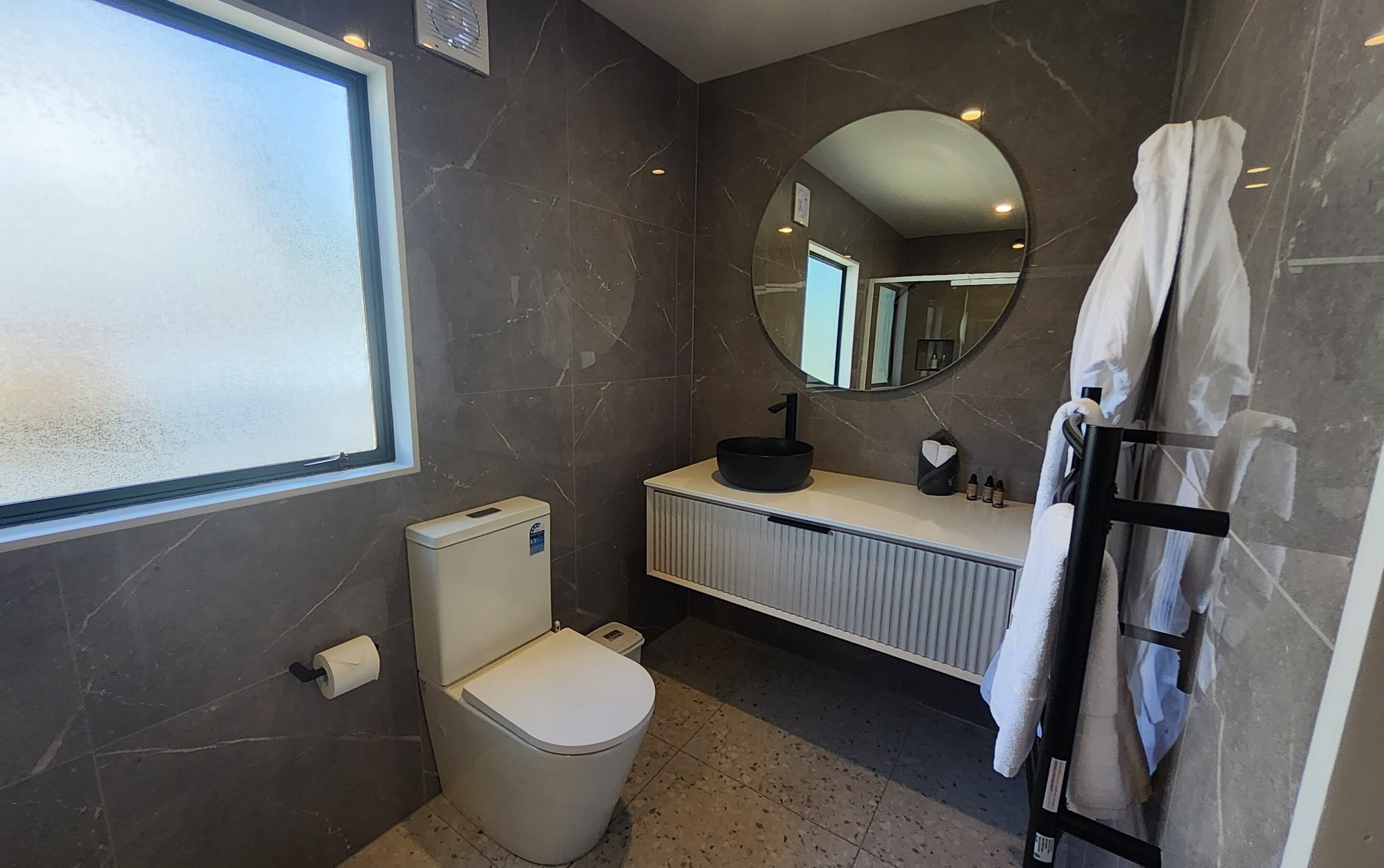 Et moderne badeværelse med toilet, vask og spejl.