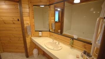 A wooden cabin bathroom with a large mirror, a sink, and a toilet.