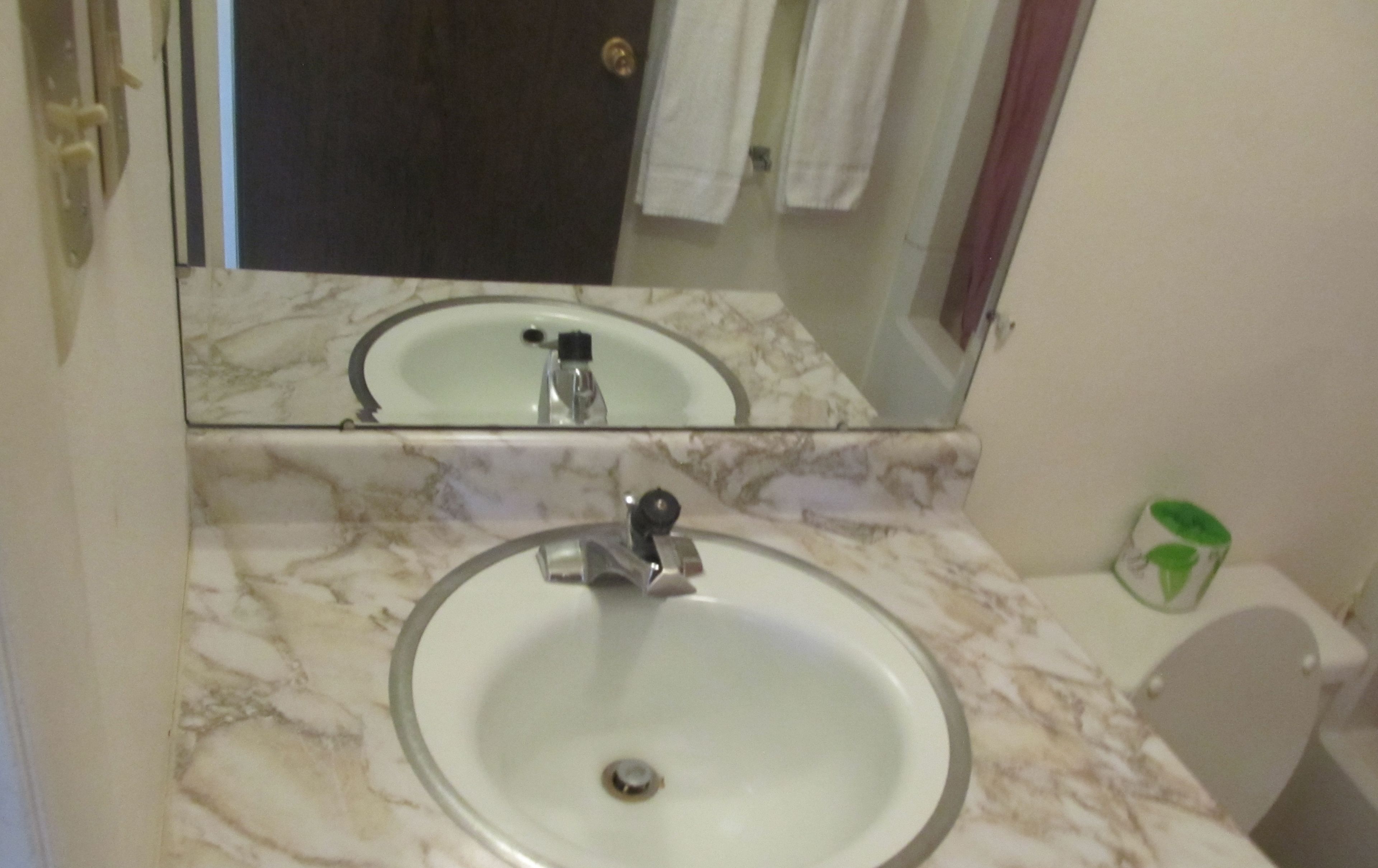A bathroom with a marble sink, a mirror, and a toilet.