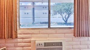 Una habitación con un ventanal grande, una pared de ladrillo y un equipo de aire acondicionado.