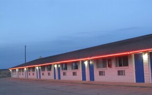 A motel with a row of rooms, each with a blue door and a small window.