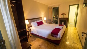 A hotel room with a large bed, wooden flooring, a wardrobe, a desk, and a fireplace. - El Andariego (Cusco)