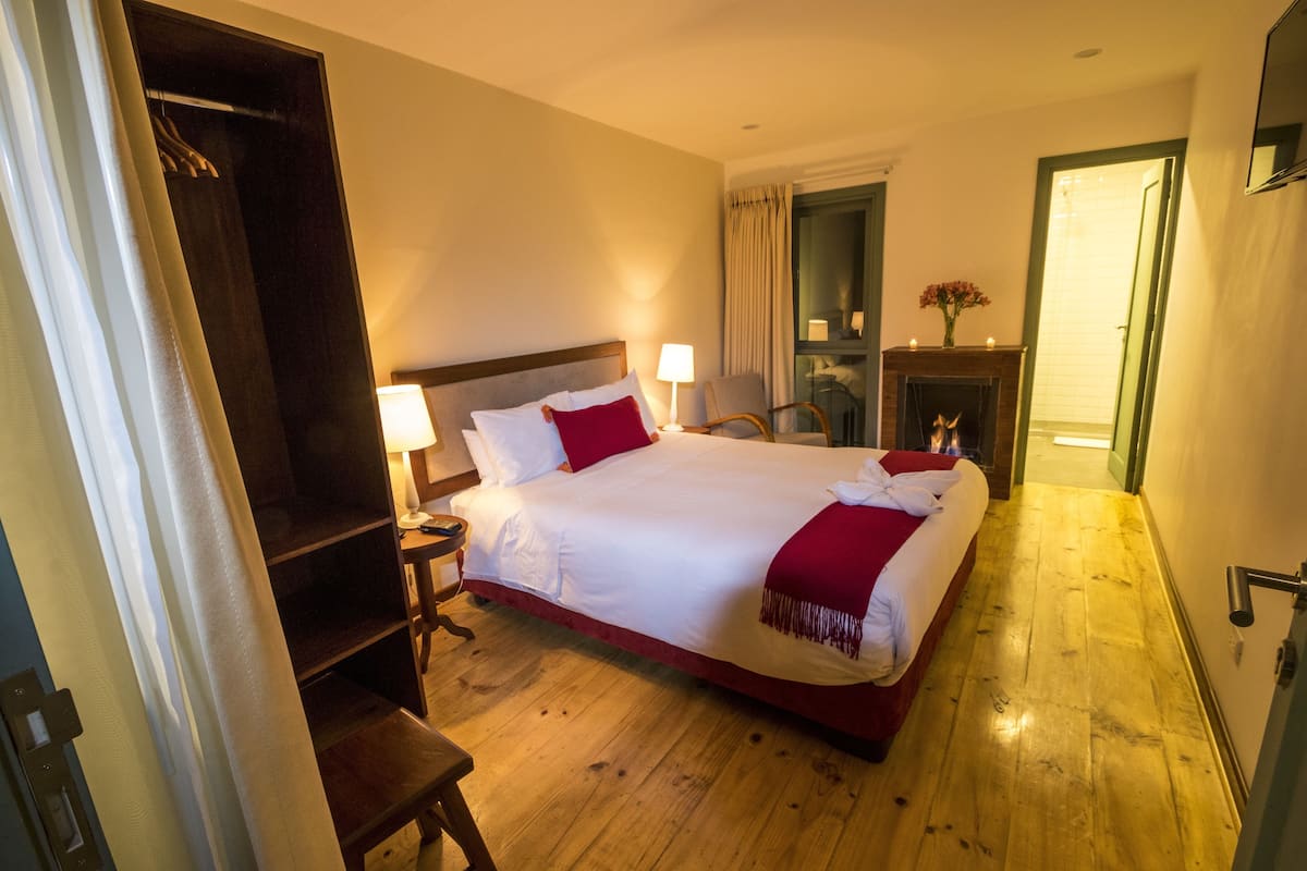 Ein Hotelzimmer mit einem großen Bett, Holzboden, einem Kleiderschrank, einem Schreibtisch und einem Kamin.