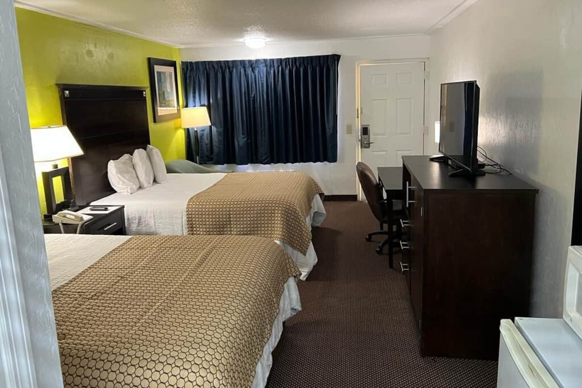A hotel room with two beds, a desk, a television, and a wardrobe.