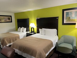 A hotel room with two beds, a desk, a chair, and a lamp. - Driftwood Inn (Lake City)