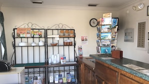 A reception area with a wooden counter, a clock, and various informational posters and brochures on the walls. - The Anastasia Inn (St. Augustine)