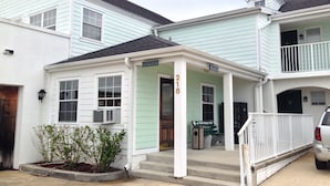 A two-story building with a light green facade, a covered porch, and a sign indicating it is an office. - The Anastasia Inn (St. Augustine)