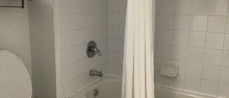 A bathroom with a toilet, bathtub, and a shower curtain.
