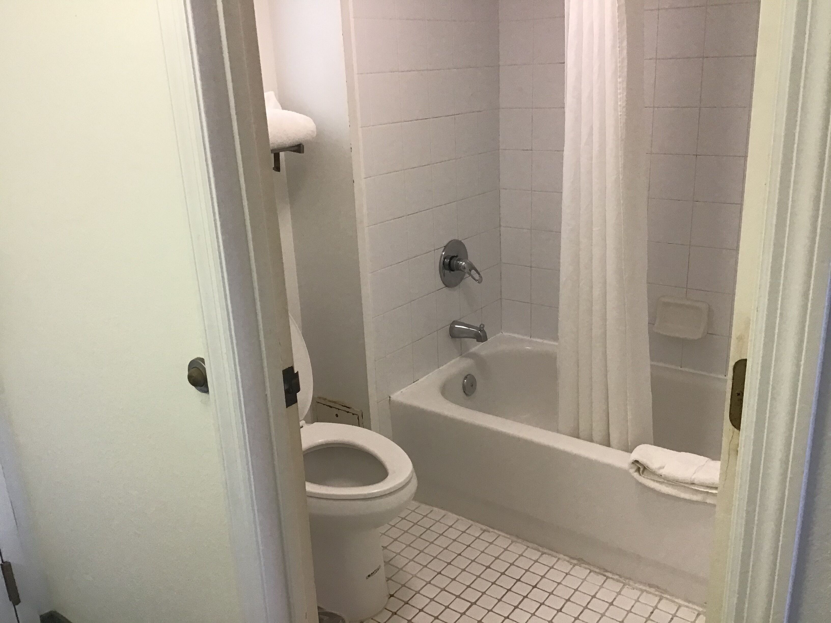 Une salle de bain équipée de toilettes, d’une baignoire et d’un rideau de douche.