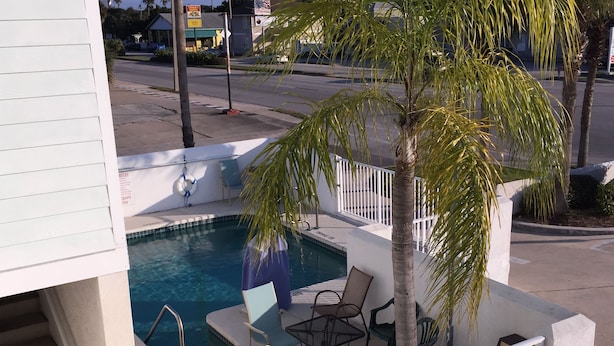 A pool area with a small pool, chairs, and a palm tree. - The Anastasia Inn (St. Augustine)