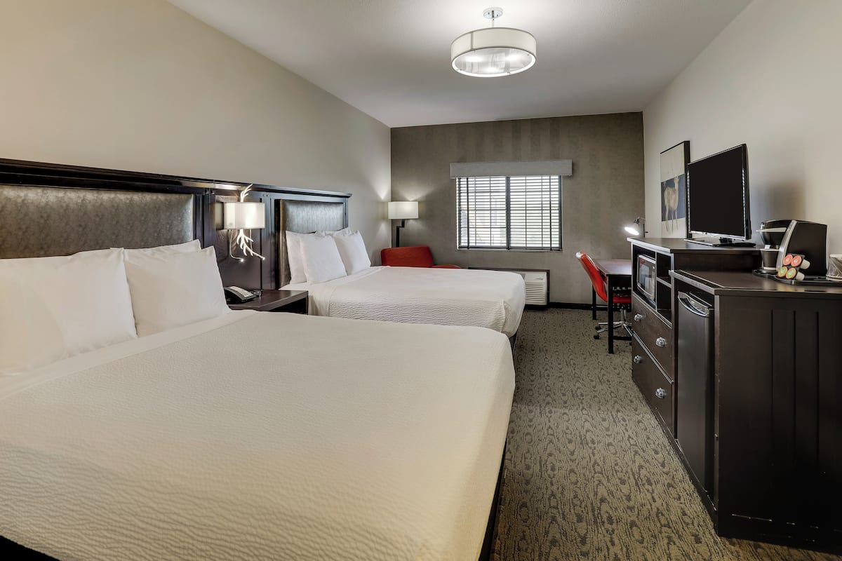 Une chambre d’hôtel avec deux lits, un bureau, une télévision et un minibar.