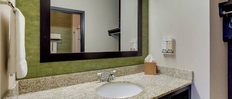 A bathroom with a large mirror, a sink, and a towel rack.