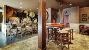 Een bar met houten stoelen, een toog en een muur met motieven van vaten.