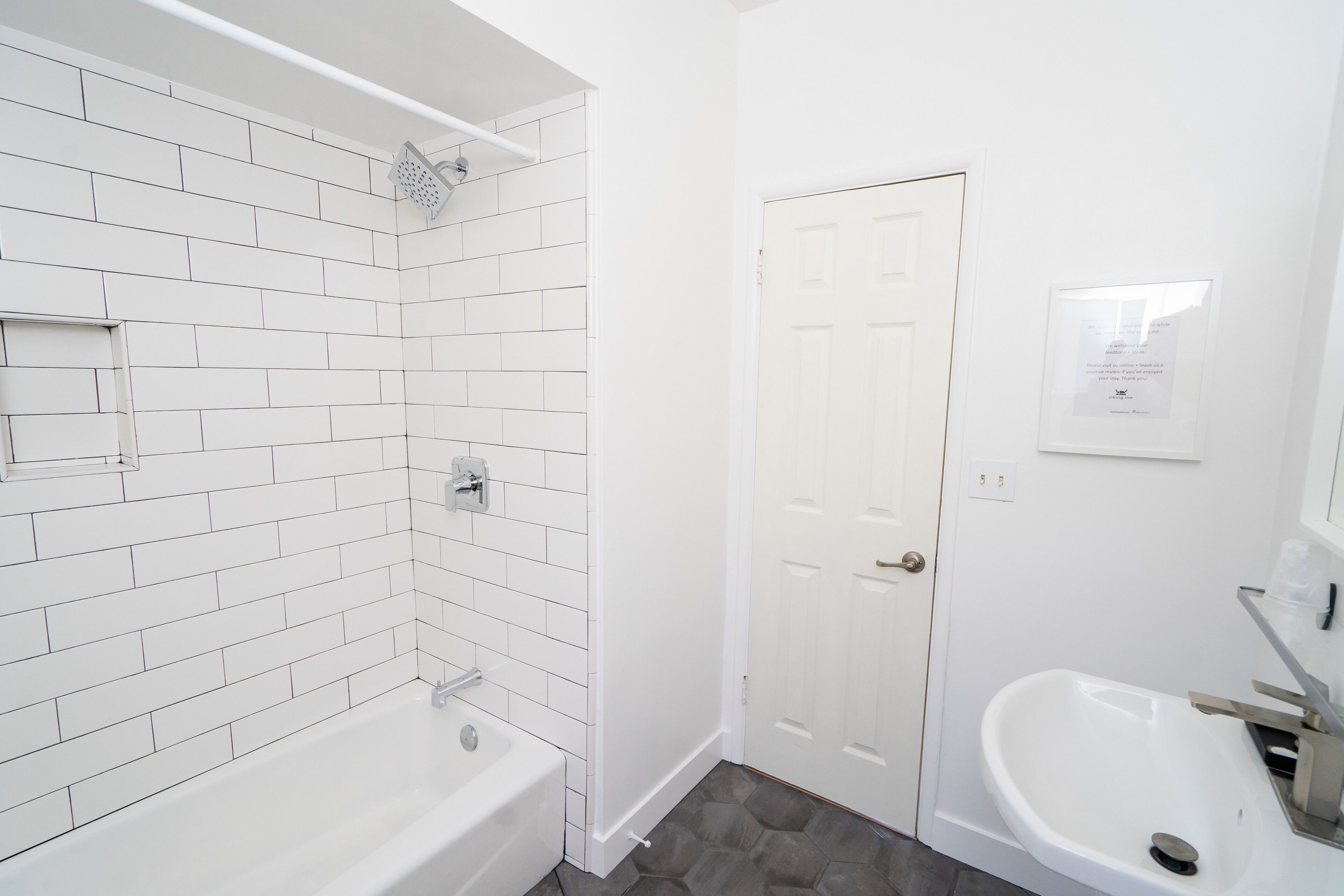 A bathroom with white subway tiles, a white bathtub, a white sink, and a shower with a white door.