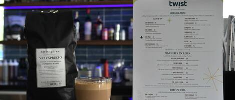 Een koffiezak met de tekst 'strongtree' en een menukaart getiteld 'twist' in een café.