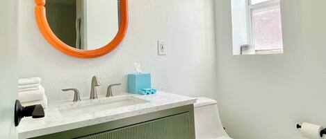 Une salle de bain avec un lavabo blanc, un meuble-lavabo vert et des toilettes blanches.