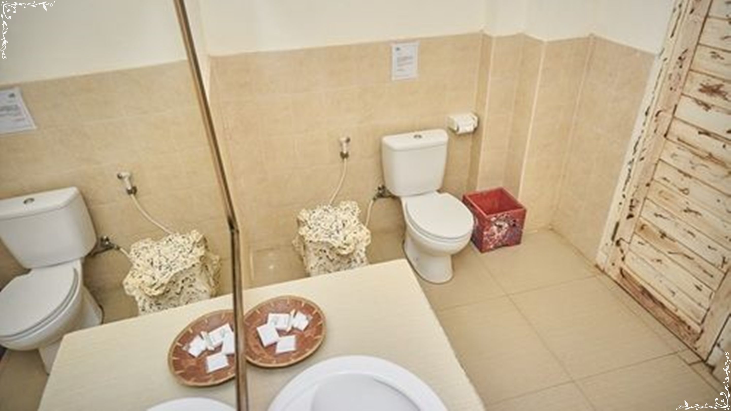 Un baño con dos inodoros, un lavabo y un espejo.