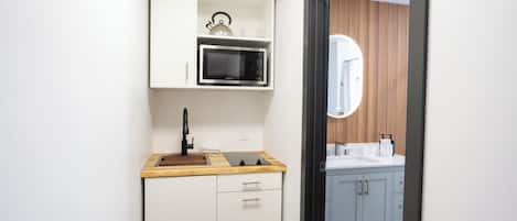 A modern kitchen with a microwave, kettle, and kettle holder on the countertop.