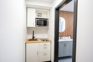 A modern kitchen with a microwave, kettle, and kettle holder on the countertop. - Sunshine Lodge (Gibsons)