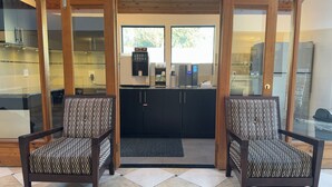 A modern kitchen with black cabinets, a coffee machine, and a refrigerator. - Sunshine Lodge (Gibsons)