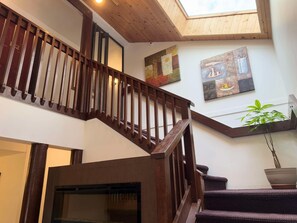 A wooden staircase with a glass door at the bottom leading to a room. - Sunshine Lodge (Gibsons)