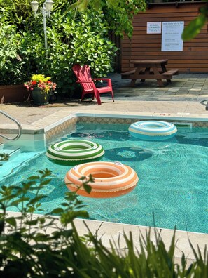 A swimming pool with three inflatable rings, a red chair, and a wooden bench. - Sunshine Lodge (Gibsons)