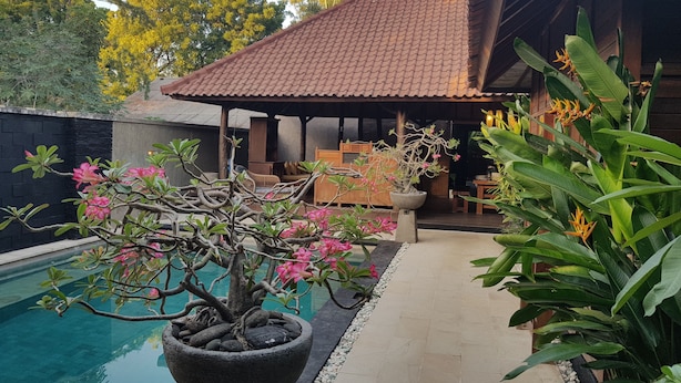 A pool area with a stone planter, a covered seating area, and surrounding greenery. - Gili Exotic Villas (Gili Trawangan)