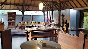 An indoor dining area with wooden furniture, a round table, and ceiling fans. - Gili Exotic Villas (Gili Trawangan)