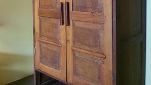 A wooden wardrobe with two doors and a shelf, featuring a metal handle and a metal latch. - Gili Exotic Villas (Gili Trawangan)
