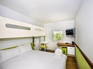 A hotel room with a bunk bed, a desk with a TV, a window, and a small kitchenette. - Ibis Budget St Peters (St Peters)