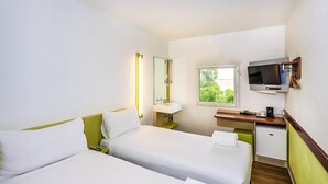 Habitación de hotel con dos camas, televisión, pequeño escritorio con espejo, ventana y refrigerador.