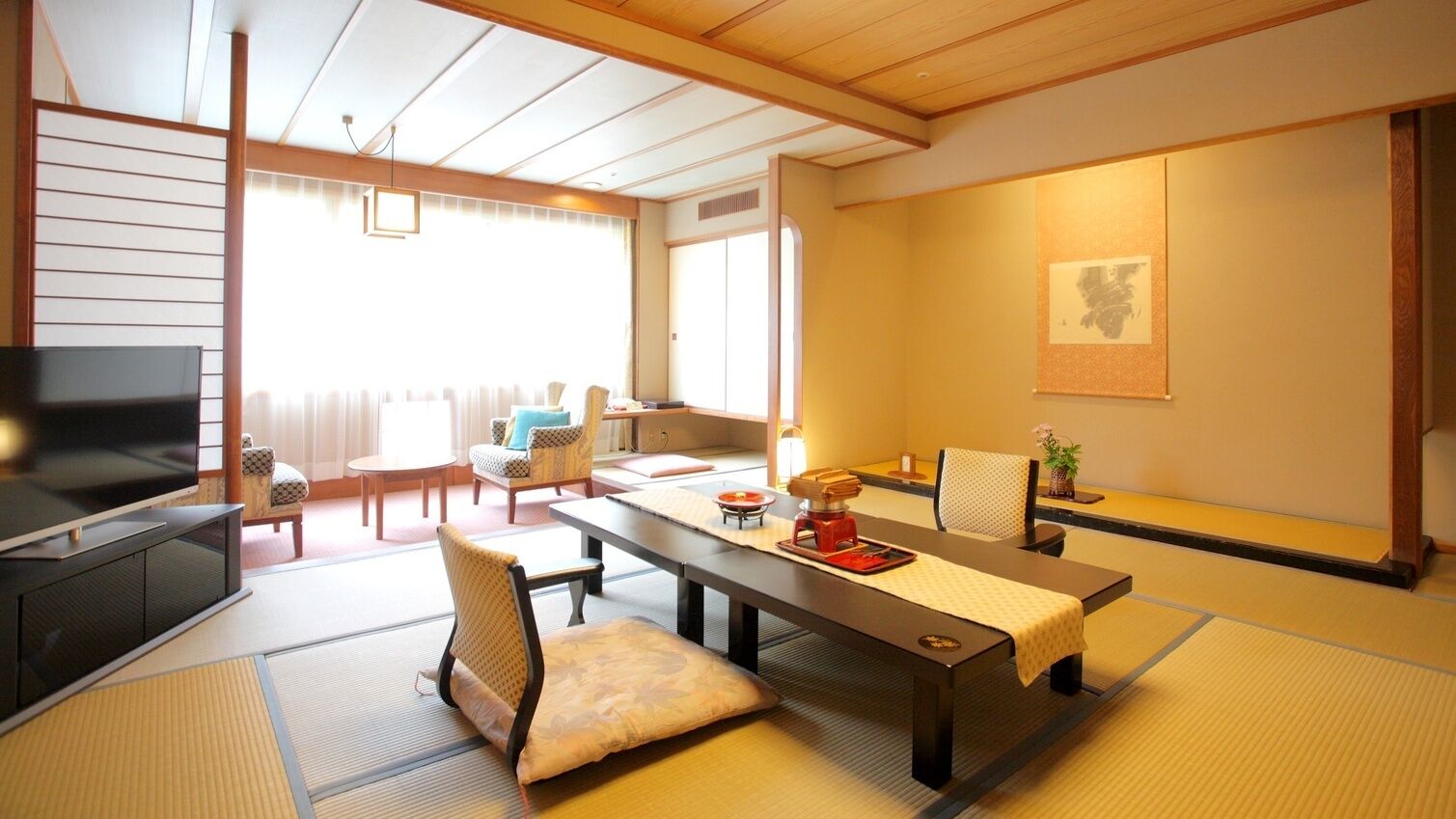 A traditional Japanese room with tatami flooring, a low table with a red tray, a television, and a sliding door leading to another room.