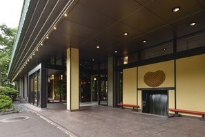 Entrada moderna de un edificio con puertas de vidrio, un banco y un diseño con forma de corazón en la pared.