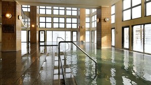 A spacious indoor swimming pool with clear views through large windows, a central staircase, and a polished floor. - Hotel Shikanoyu (Sapporo)