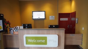 Een receptiebalie met een 'Welcome'-bord, een computerbeeldscherm en een bord met 'Managers on Duty'.