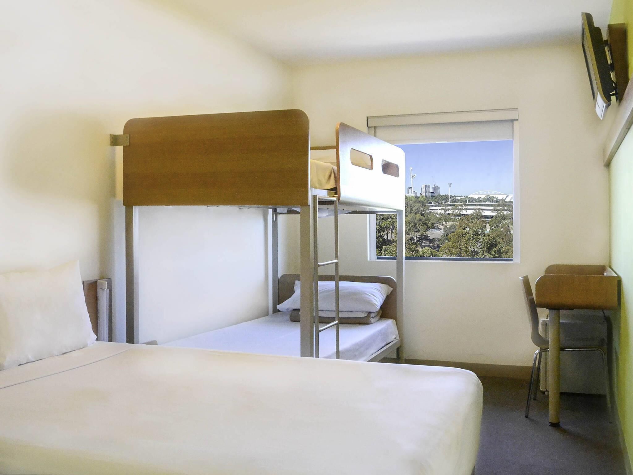 A bunk bed room with a window view of a cityscape.