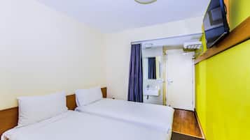 A hotel room with two beds, a bathroom with a sink and mirror, and a television mounted on the wall.