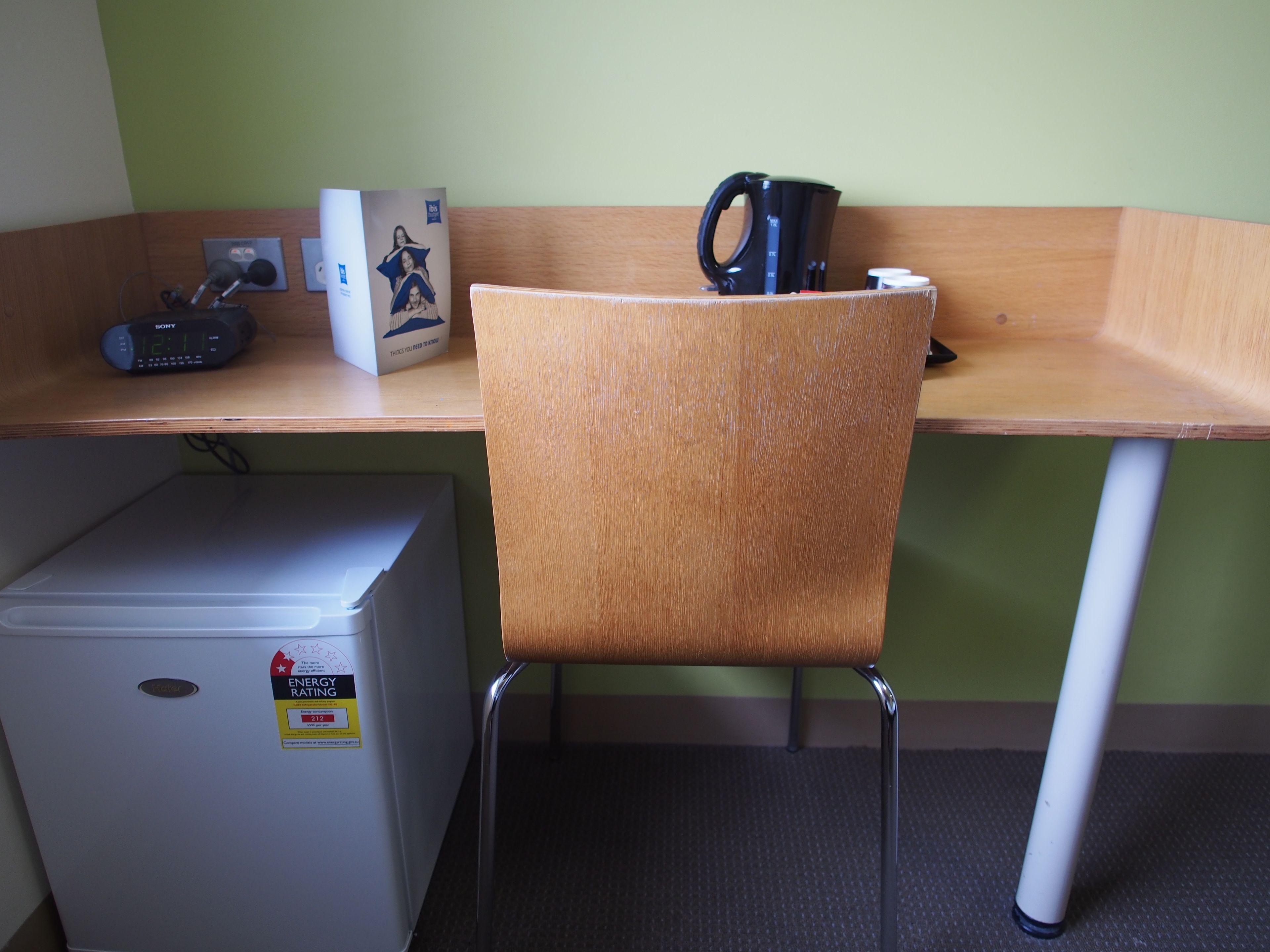 A small kitchenette with a refrigerator, a microwave, and a coffee maker on a wooden desk.