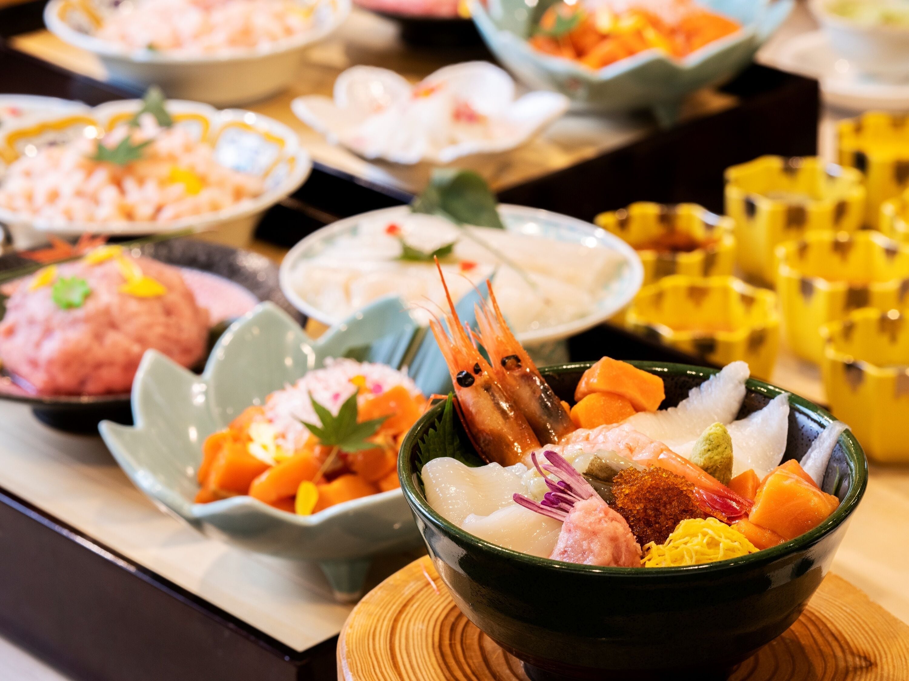 Diversos platos en cuencos, incluyendo mariscos y verduras, dispuestos sobre una mesa.