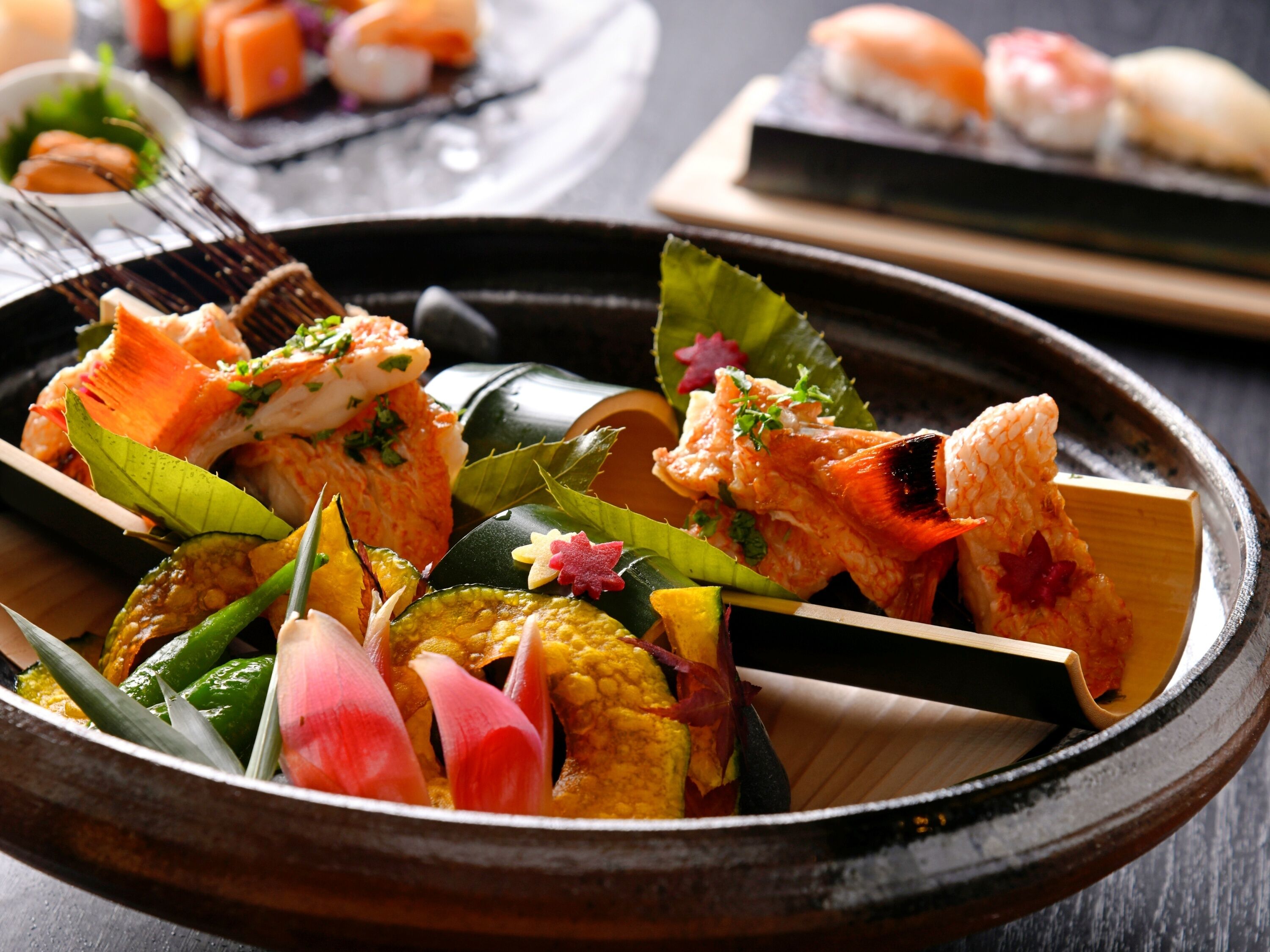 A traditional Japanese meal with various dishes, including sashimi and vegetables, served on a wooden table.