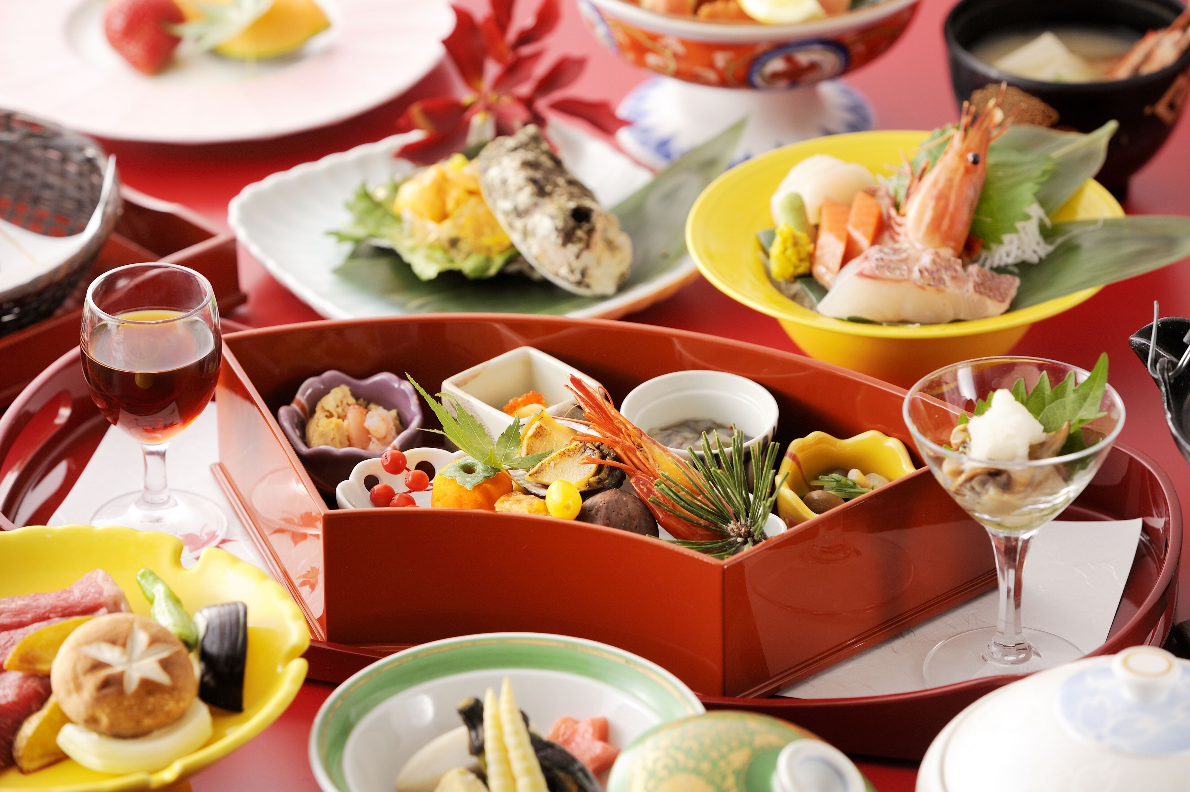 A variety of dishes and drinks on a table, including seafood, vegetables, and a glass of wine.