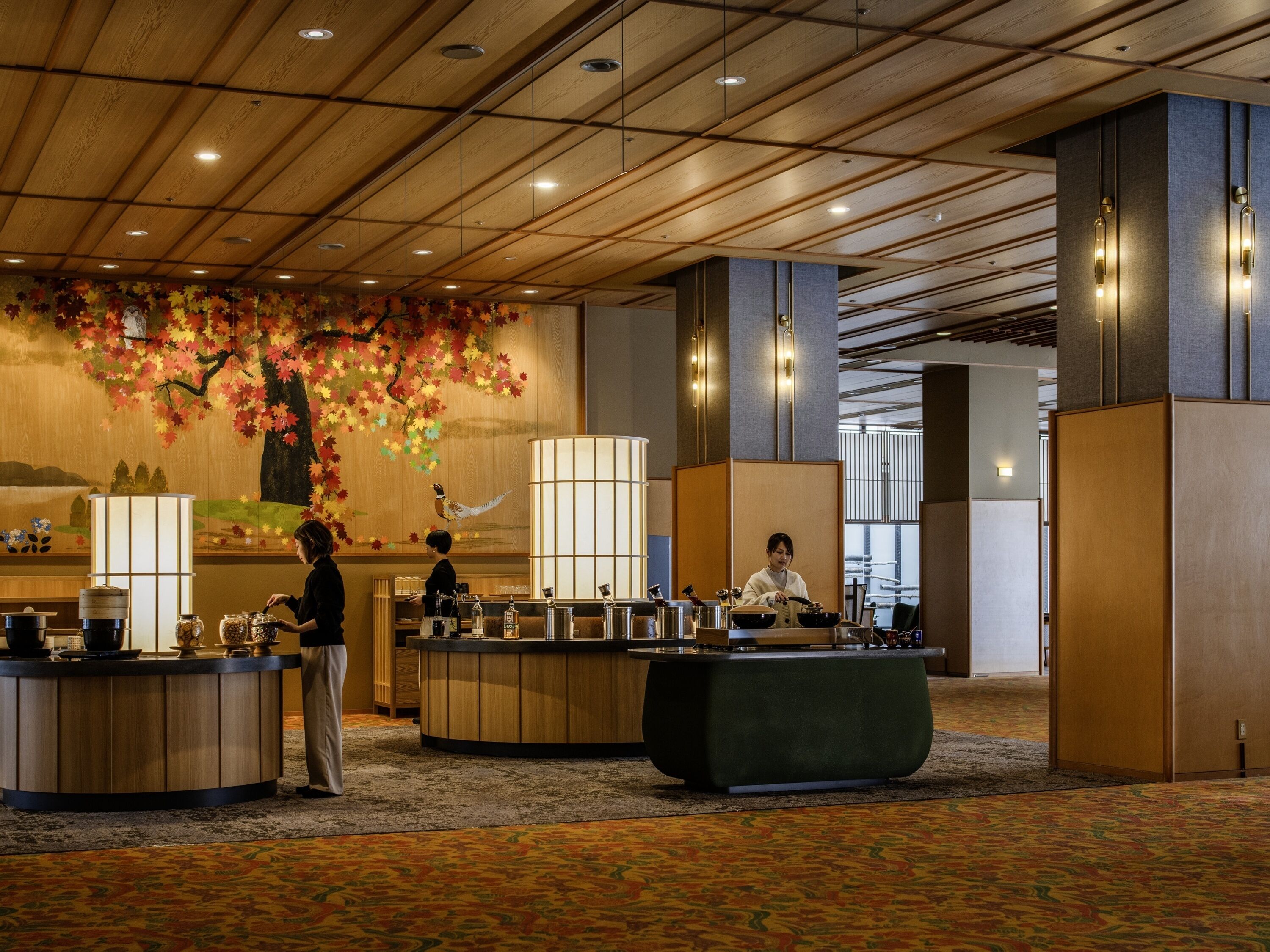 A hotel lobby with a reception desk, a large decorative wall, and a carpeted floor.